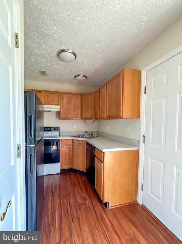 22565 Upper Kells Ln, Great Mills, MD 20634 - kitchen with black appliances, under cabinet range hood, dark wood-type flooring, a sink, and a textured ceiling