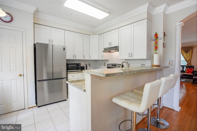 4057 Glostonbury Way, Fairfax, VA 22030 - kitchen featuring freestanding refrigerator, black microwave, under cabinet range hood, crown molding, and light stone countertops