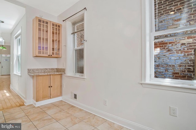743 W Cross St, Baltimore, MD 21230 - kitchen featuring glass insert cabinets, light tile patterned floors, and light stone countertops