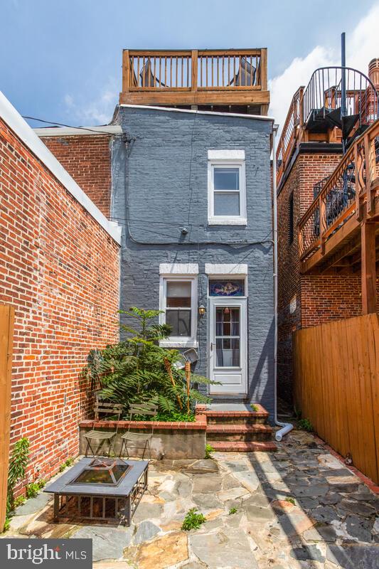 743 W Cross St, Baltimore, MD 21230 - rear view of house with brick siding, a fire pit, a patio, and a balcony