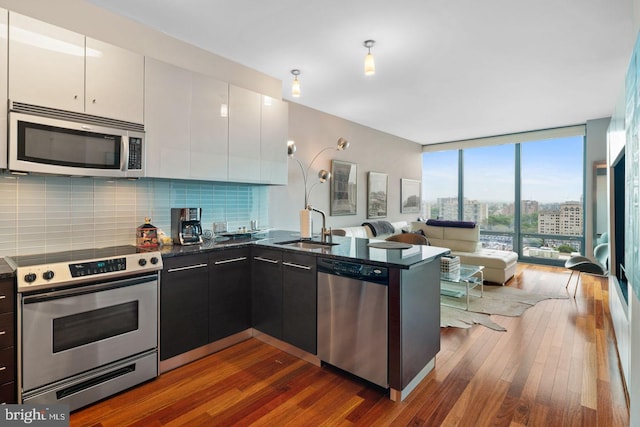 2101 Market St Unit 3408, Philadelphia, PA 19103 - kitchen with stainless steel appliances, a sink, dark wood-style flooring, decorative backsplash, and white cabinetry