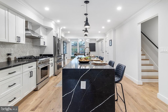 1242 Meigs Pl NE Unit C, Washington, DC 20002 - kitchen with stainless steel appliances, wall chimney exhaust hood, crown molding, light wood-type flooring, and a center island with sink