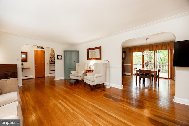 337 Greene Rd, Berwyn, PA 19312 - living room featuring arched walkways, a chandelier, a baseboard heating unit, wood finished floors, and ornamental molding