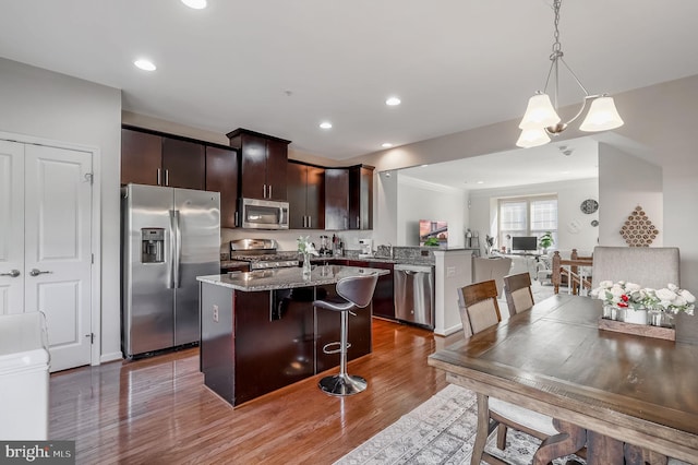2620 Egret Way, Frederick, MD 21701 - kitchen with stainless steel appliances, a kitchen bar, a peninsula, dark brown cabinets, and wood finished floors