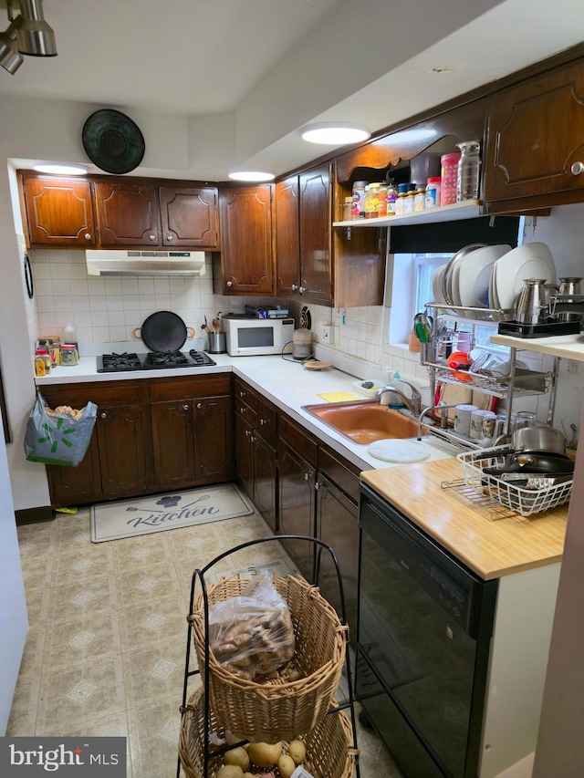 9618 Hoff St, Philadelphia, PA 19115 - kitchen featuring white microwave, under cabinet range hood, tasteful backsplash, a sink, and black gas stovetop