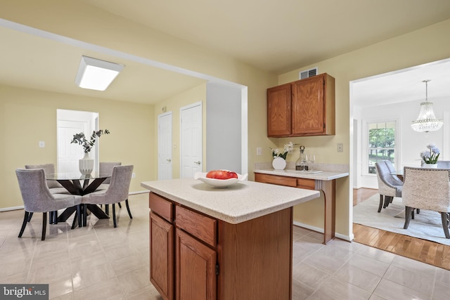 13412 Glen Taylor Ln, Herndon, VA 20171 - kitchen featuring light countertops, a chandelier, brown cabinets, a kitchen island, and hanging light fixtures