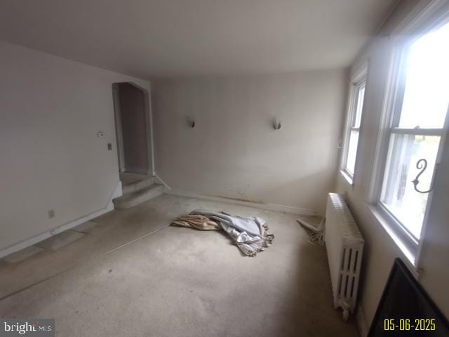608 Chestnut Hill Ave, Baltimore, MD 21218 - unfurnished living room with radiator, carpet floors, arched walkways, baseboards, and stairway