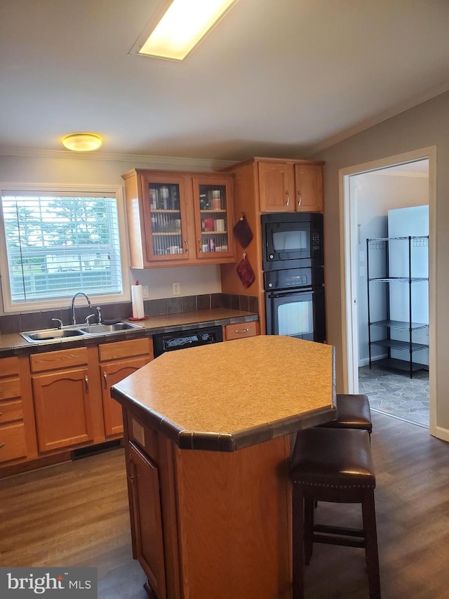 113 Beech Tree Ln, Harrington, DE 19952 - kitchen featuring black appliances, a sink, a breakfast bar, ornamental molding, and a kitchen island