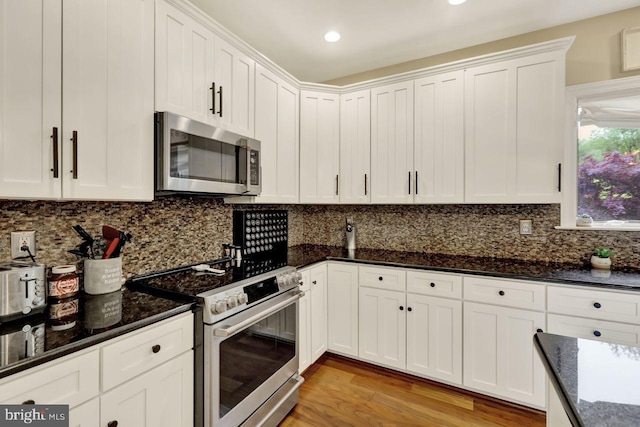 12 Fox Glen Dr, Reading, PA 19608 - kitchen featuring appliances with stainless steel finishes, white cabinets, light wood-style floors, dark stone counters, and tasteful backsplash