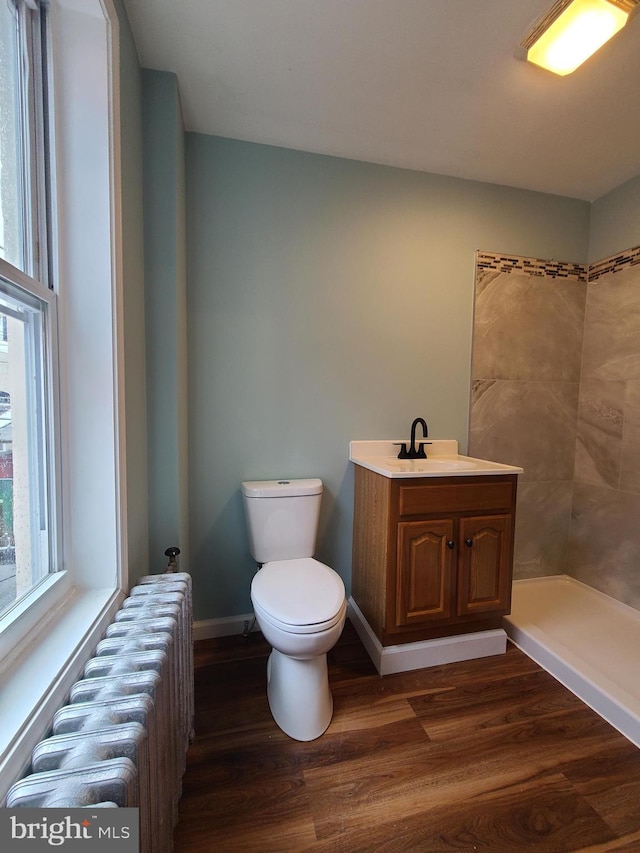 1218 Fidelity St, Reading, PA 19604 - bathroom featuring radiator, toilet, wood finished floors, a tile shower, and vanity