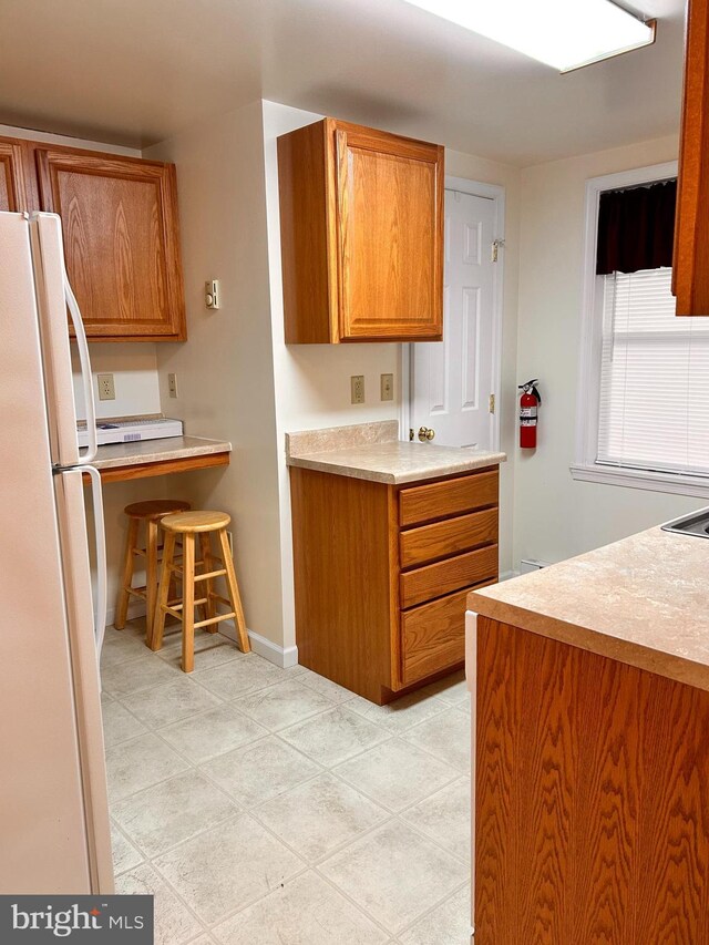 110-112 W Bishop St, Bellefonte, PA 16823 - kitchen featuring freestanding refrigerator, light countertops, brown cabinets, and baseboards