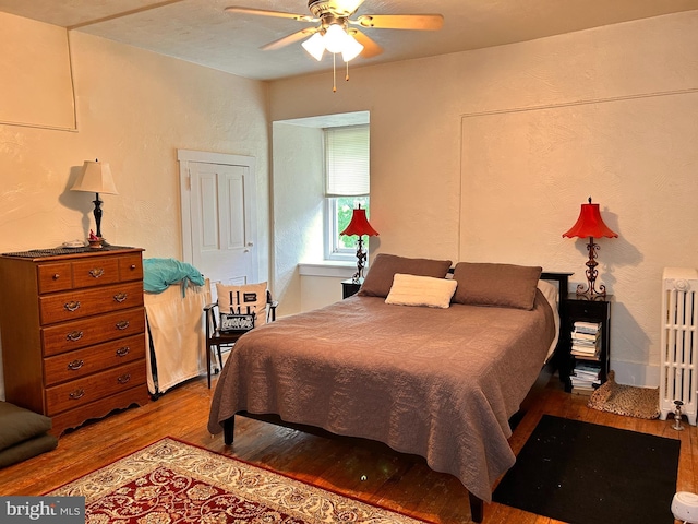 110-112 W Bishop St, Bellefonte, PA 16823 - bedroom featuring wood finished floors, radiator, a textured wall, and ceiling fan