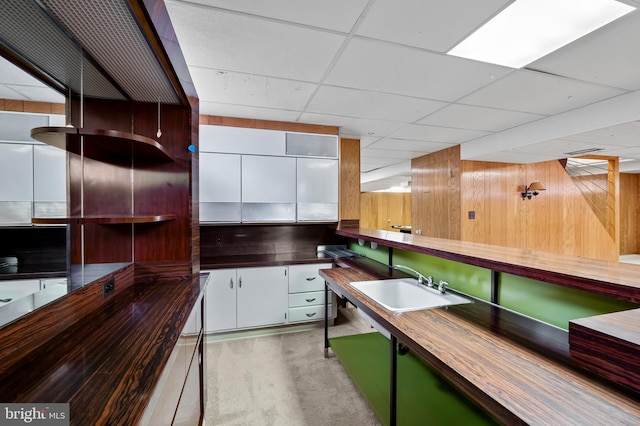 8320 Overmont, Parkville, MD 21234 - kitchen featuring a sink, wooden walls, a paneled ceiling, and white cabinetry