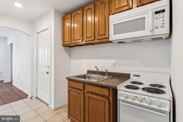 1707 H St NE, Washington, DC 20002 - kitchen with white appliances, a sink, arched walkways, brown cabinetry, and dark countertops