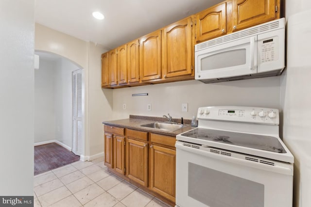 1707 H St NE, Washington, DC 20002 - kitchen with white appliances, a sink, arched walkways, dark countertops, and light tile patterned floors