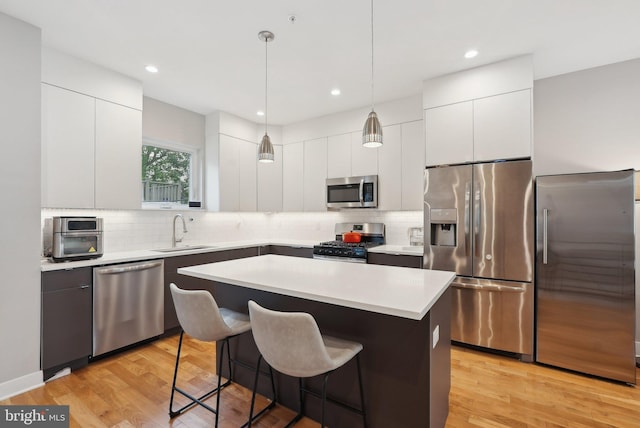 2811 Wharton St, Philadelphia, PA 19146 - kitchen featuring appliances with stainless steel finishes, a sink, modern cabinets, a breakfast bar, and decorative backsplash