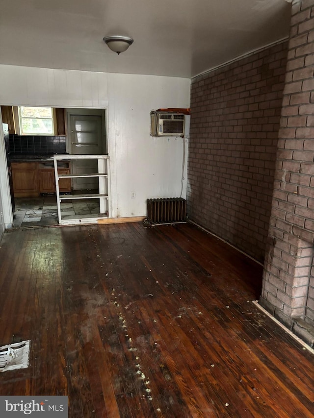 1436 S Etting St, Philadelphia, PA 19146 - unfurnished living room with dark wood-type flooring, radiator heating unit, an AC wall unit, and brick wall