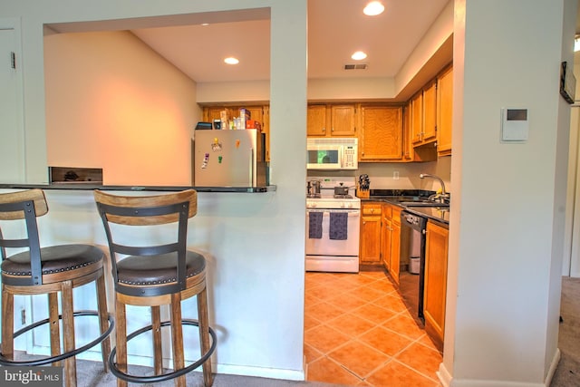 304 Trinity Ct Unit 11, Princeton, NJ 08540 - kitchen featuring white appliances, a sink, recessed lighting, a breakfast bar area, and brown cabinetry