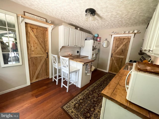 4306 National Pike, Markleysburg, PA 15459 - kitchen featuring white appliances, butcher block countertops, dark wood-type flooring, a textured ceiling, and white cabinetry