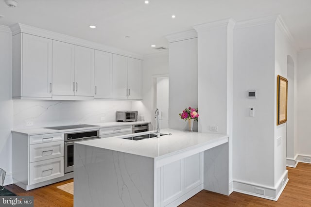 1901 Walnut St Unit 20E, Philadelphia, PA 19103 - kitchen with oven, black electric cooktop, crown molding, white cabinets, and a peninsula