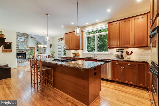 4510 Fish Hawk Ct, Chesapeake Beach, MD 20732 - kitchen with stainless steel appliances, a center island, light wood finished floors, tasteful backsplash, and dark stone countertops