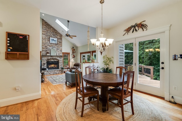 4510 Fish Hawk Ct, Chesapeake Beach, MD 20732 - dining room with a stone fireplace, light wood-style flooring, a chandelier, ceiling fan, and high vaulted ceiling