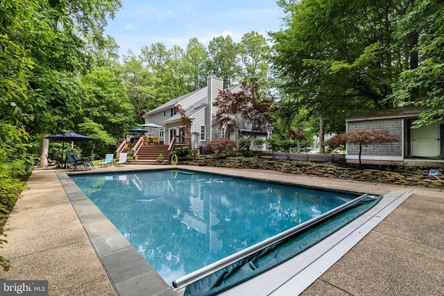 4510 Fish Hawk Ct, Chesapeake Beach, MD 20732 - view of pool featuring a deck, a covered pool, an outdoor structure, stairway, and view of scattered trees