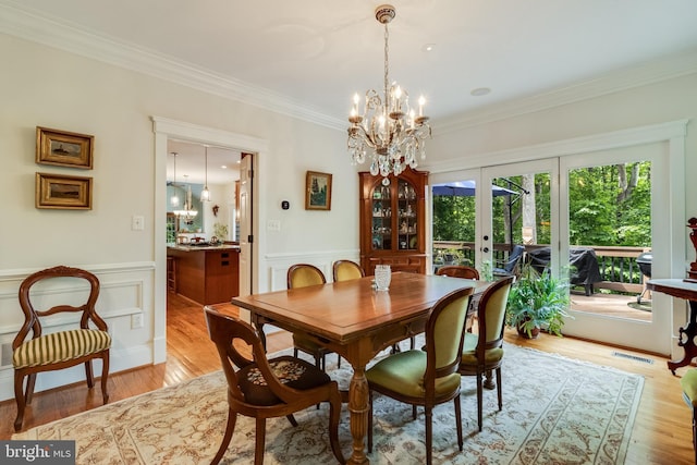4510 Fish Hawk Ct, Chesapeake Beach, MD 20732 - dining room featuring french doors, a chandelier, ornamental molding, a wainscoted wall, and light wood finished floors