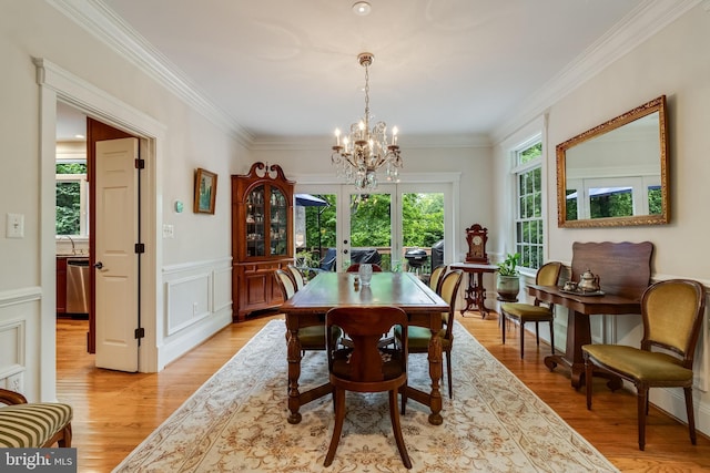 4510 Fish Hawk Ct, Chesapeake Beach, MD 20732 - dining space featuring a chandelier, light wood-style floors, crown molding, a wainscoted wall, and a decorative wall