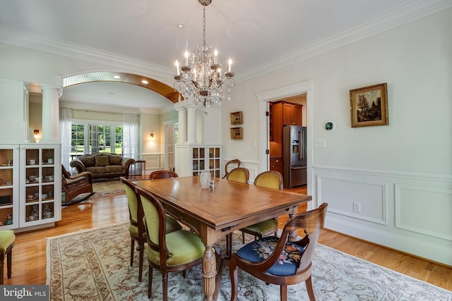 4510 Fish Hawk Ct, Chesapeake Beach, MD 20732 - dining room featuring crown molding, ornate columns, a chandelier, light wood finished floors, and wainscoting