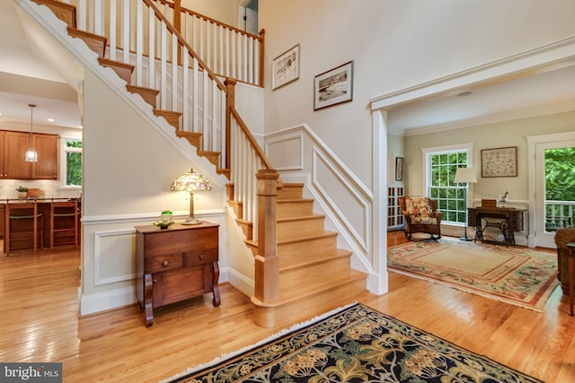 4510 Fish Hawk Ct, Chesapeake Beach, MD 20732 - staircase with wood finished floors, a high ceiling, a decorative wall, crown molding, and a wainscoted wall