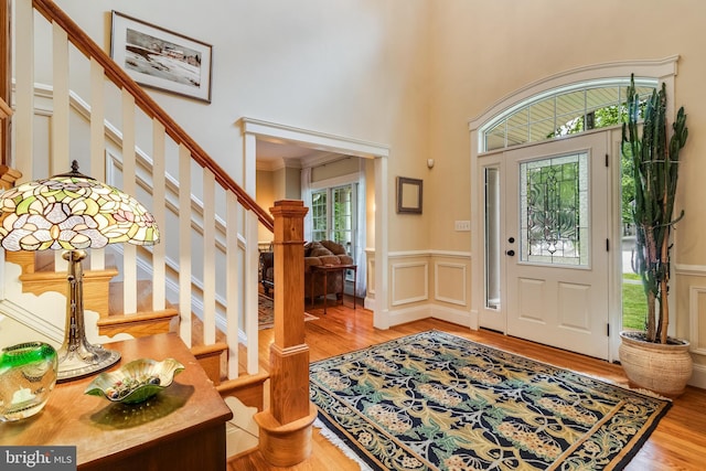 4510 Fish Hawk Ct, Chesapeake Beach, MD 20732 - foyer featuring wood finished floors, stairs, a wainscoted wall, a decorative wall, and a high ceiling