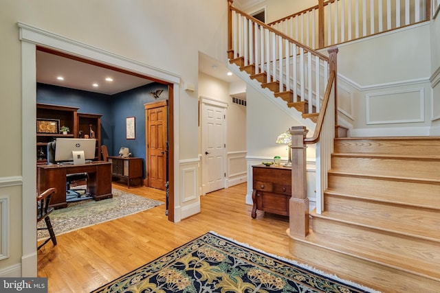 4510 Fish Hawk Ct, Chesapeake Beach, MD 20732 - stairs featuring wood finished floors, wainscoting, a decorative wall, and a towering ceiling