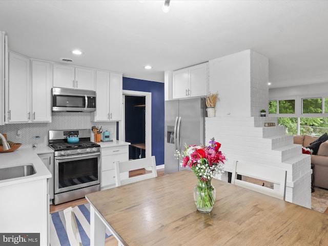 5902 Amelia St, Springfield, VA 22150 - kitchen featuring appliances with stainless steel finishes, tasteful backsplash, white cabinetry, a sink, and light countertops