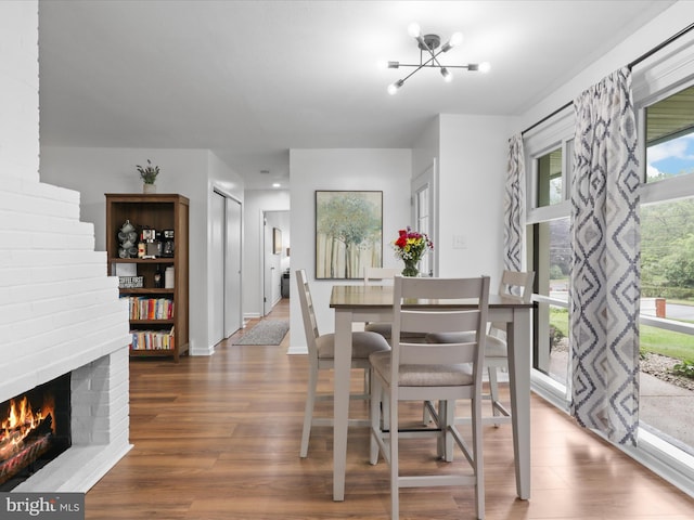5902 Amelia St, Springfield, VA 22150 - dining space featuring wood finished floors, a chandelier, a brick fireplace, and baseboards