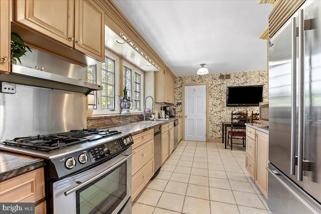 716 Old Gulph Rd, Bryn Mawr, PA 19010 - kitchen with stainless steel appliances, wallpapered walls, a sink, light tile patterned floors, and dark stone countertops