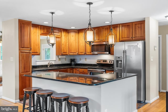 1157 Pine Tree Dr, Annapolis, MD 21409 - kitchen featuring appliances with stainless steel finishes, recessed lighting, brown cabinetry, decorative light fixtures, and light wood-type flooring