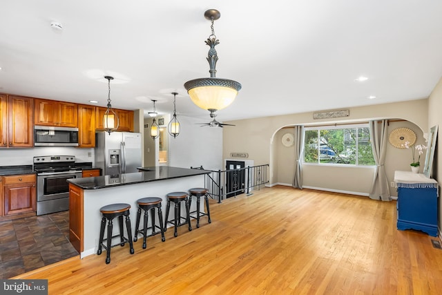 1157 Pine Tree Dr, Annapolis, MD 21409 - kitchen with appliances with stainless steel finishes, arched walkways, dark countertops, a breakfast bar area, and ceiling fan