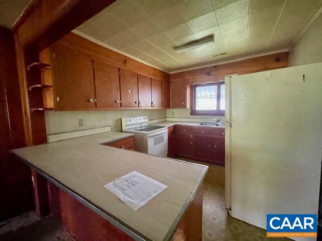 24 E 1st St, Craigsville, VA 24430 - kitchen with white appliances, a peninsula, a sink, light countertops, and brown cabinets
