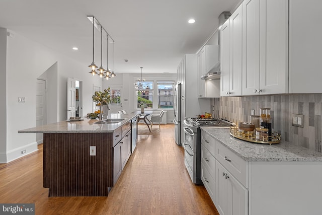 3551 13th St NW, Washington, DC 20010 - kitchen with appliances with stainless steel finishes, a sink, light wood-type flooring, backsplash, and exhaust hood