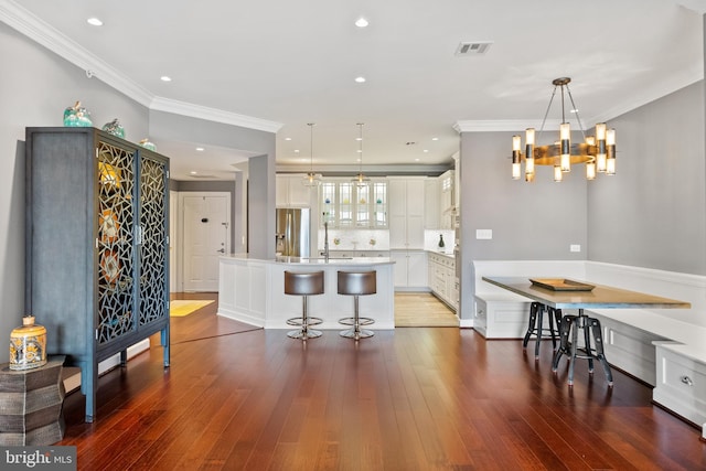 525 Belmont Bay Dr Unit 406, Woodbridge, VA 22191 - kitchen with stainless steel fridge with ice dispenser, a kitchen bar, ornamental molding, white cabinets, and a kitchen island with sink