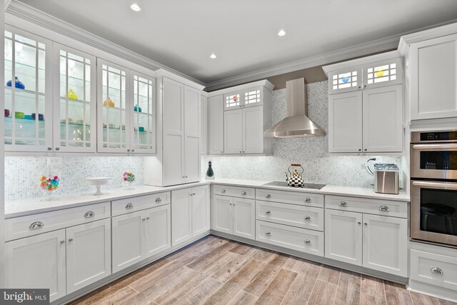 525 Belmont Bay Dr Unit 406, Woodbridge, VA 22191 - kitchen with wall chimney exhaust hood, ornamental molding, stainless steel double oven, black electric stovetop, and light countertops