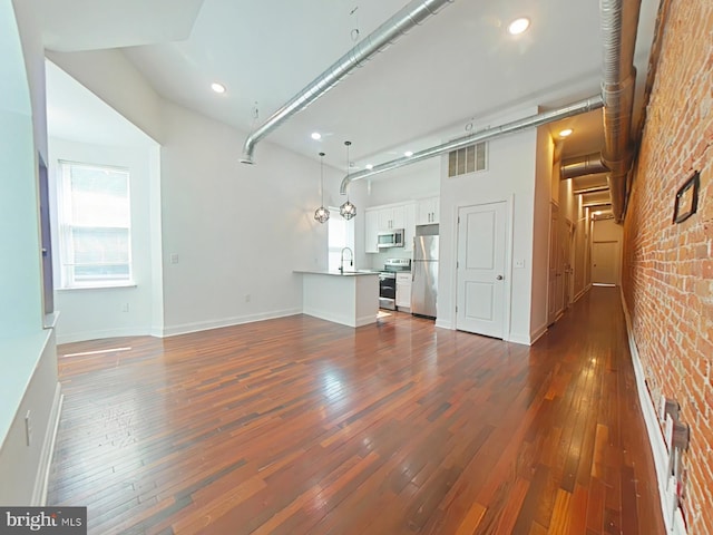 3228 W Diamond St, Philadelphia, PA 19121 - unfurnished living room featuring dark wood-style floors, brick wall, and recessed lighting