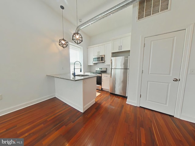 3228 W Diamond St, Philadelphia, PA 19121 - kitchen featuring appliances with stainless steel finishes, a peninsula, white cabinets, dark wood-style floors, and hanging light fixtures