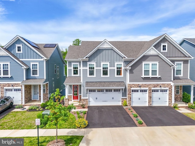17941 Woods Overlook Dr, Dumfries, VA 22026 - view of front of property featuring board and batten siding, driveway, an attached garage, stone siding, and a shingled roof