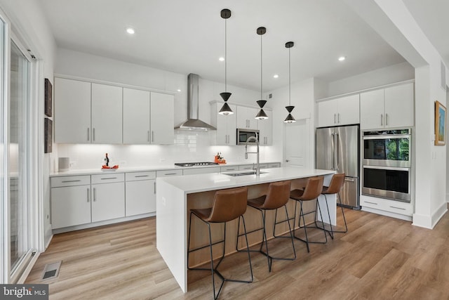 17941 Woods Overlook Dr, Dumfries, VA 22026 - kitchen featuring wall chimney exhaust hood, stainless steel appliances, a sink, a kitchen breakfast bar, and light countertops