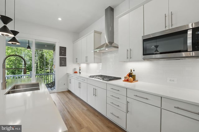 17941 Woods Overlook Dr, Dumfries, VA 22026 - kitchen featuring appliances with stainless steel finishes, a sink, wall chimney exhaust hood, light countertops, and backsplash