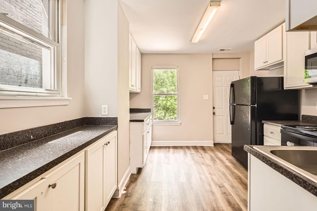 2228 W Baltimore St, Baltimore, MD 21223 - kitchen with light wood-type flooring, dark countertops, white cabinets, stainless steel microwave, and stove