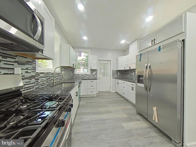 134 N Hobart St, Philadelphia, PA 19139 - kitchen with appliances with stainless steel finishes, tasteful backsplash, white cabinets, a sink, and light wood finished floors