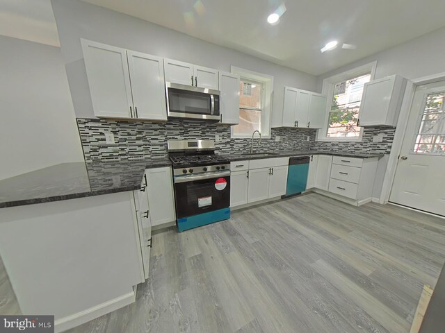 134 N Hobart St, Philadelphia, PA 19139 - kitchen featuring appliances with stainless steel finishes, a sink, a peninsula, white cabinets, and decorative backsplash